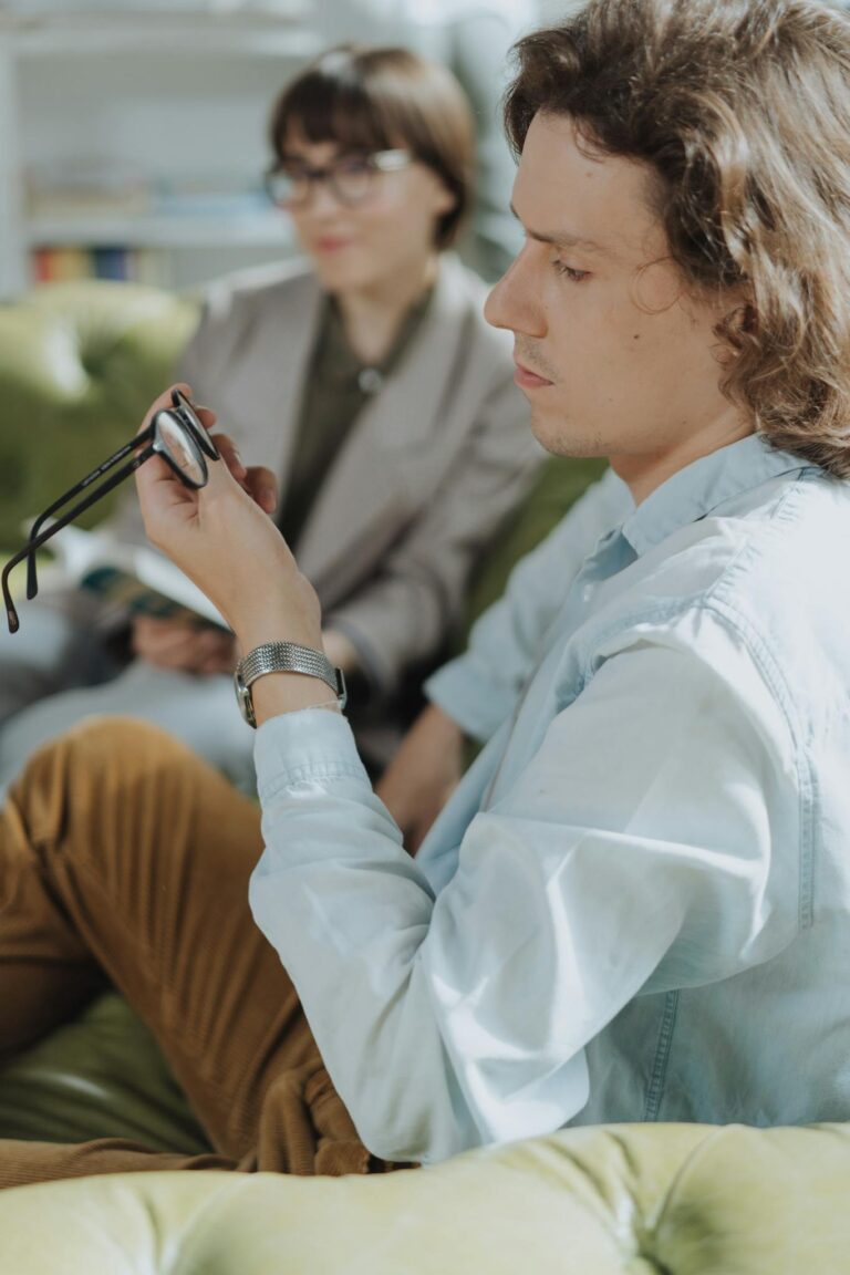 A young man and woman engage in reading and reflection on a cozy sofa indoors.
