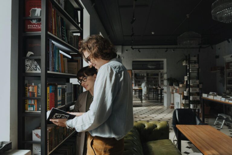 Two adults browsing books in a stylish library, sharing joy and knowledge.