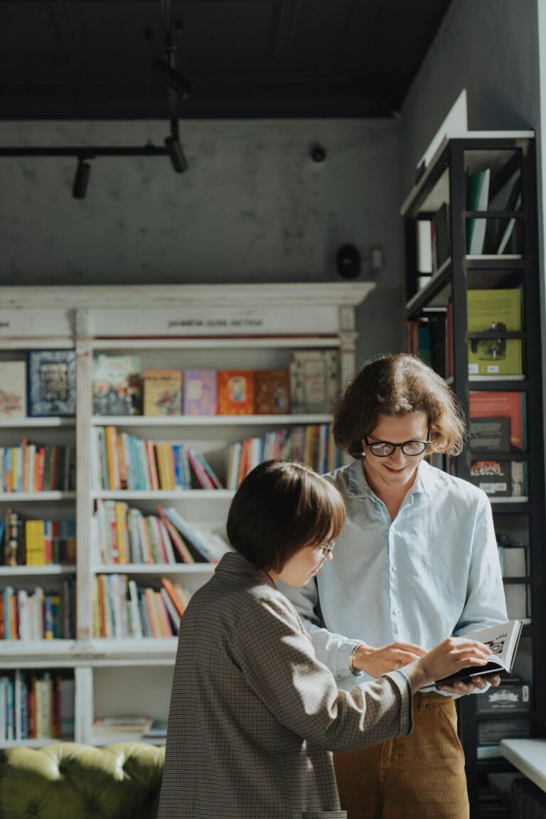 Two adults engage in a joyful book discussion in a cozy library setting.
