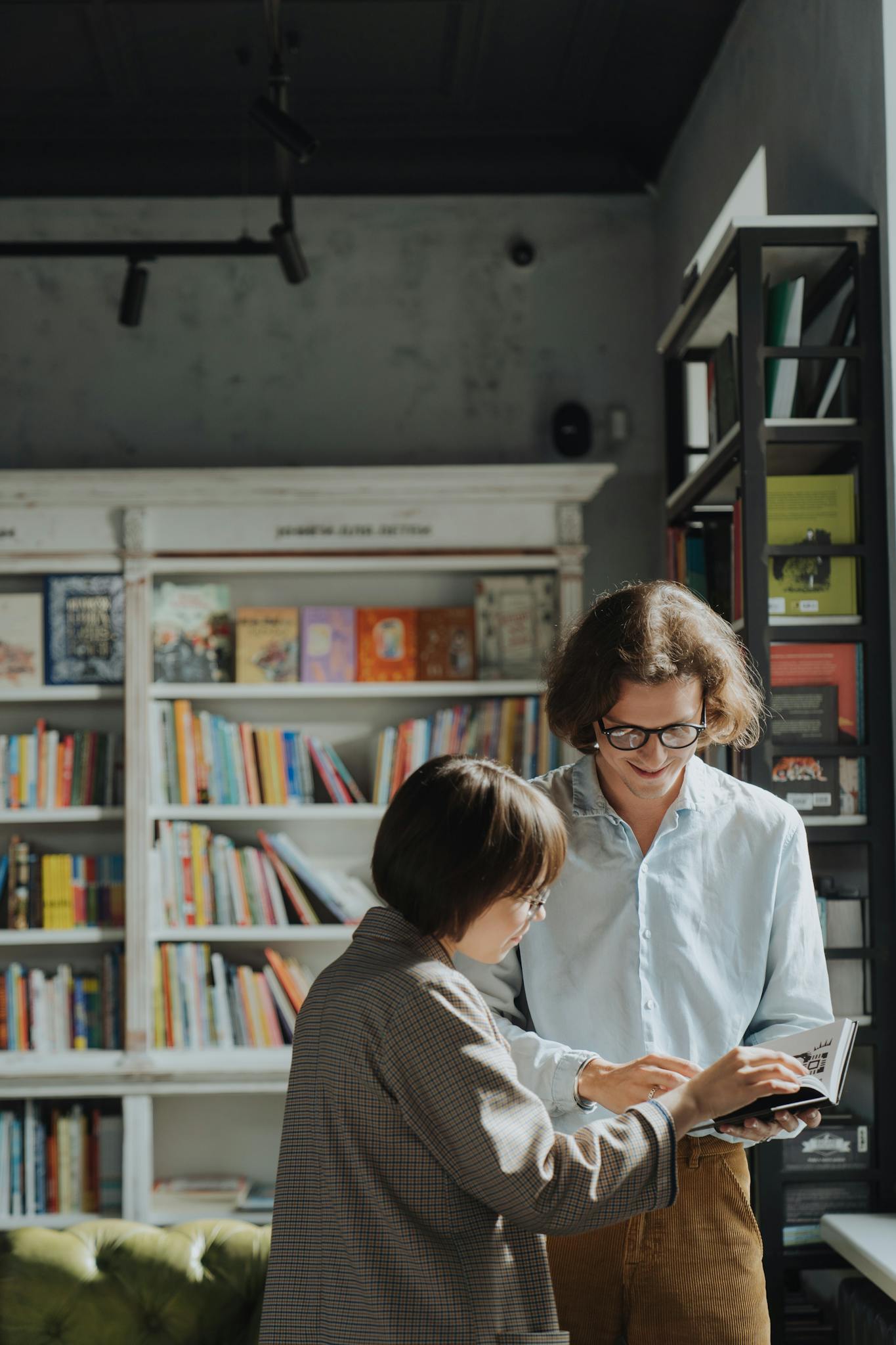 Two adults engage in a joyful book discussion in a cozy library setting.