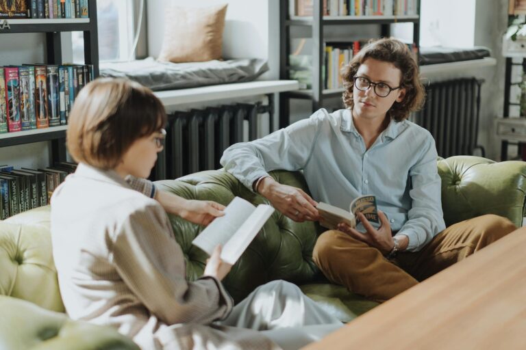 Two young adults enjoying a cozy moment reading and discussing books in a library.